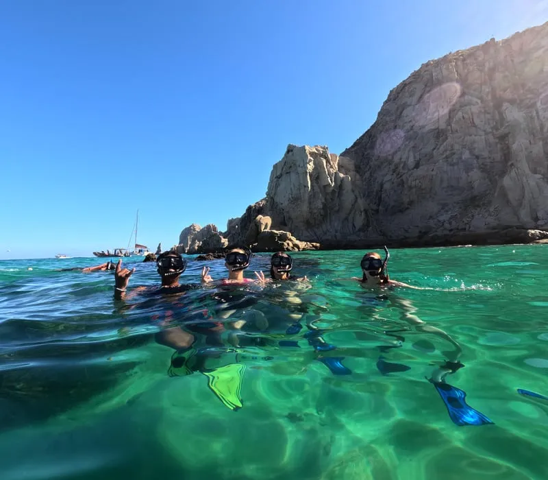 Snorkelers in clear water beside Pelican Rock on a snorkeling in Cabo San Lucas tour at Land's End