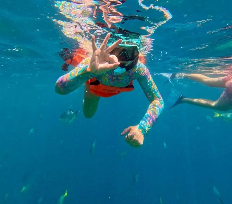 A small panga boat and snorkelers in calm morning water on a snorkeling in Cabo San Lucas excursion